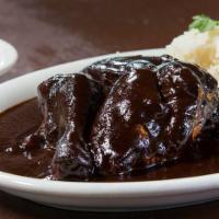 Pollo Con Mole Negro · Free range chicken in a traditional mole negro. Served with herbed white rice, chiles en vin...