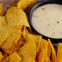 Chips & Queso · Creamy white cheddar cheese, ground green chilies, diced onion, garlic and jalapeño with hou...