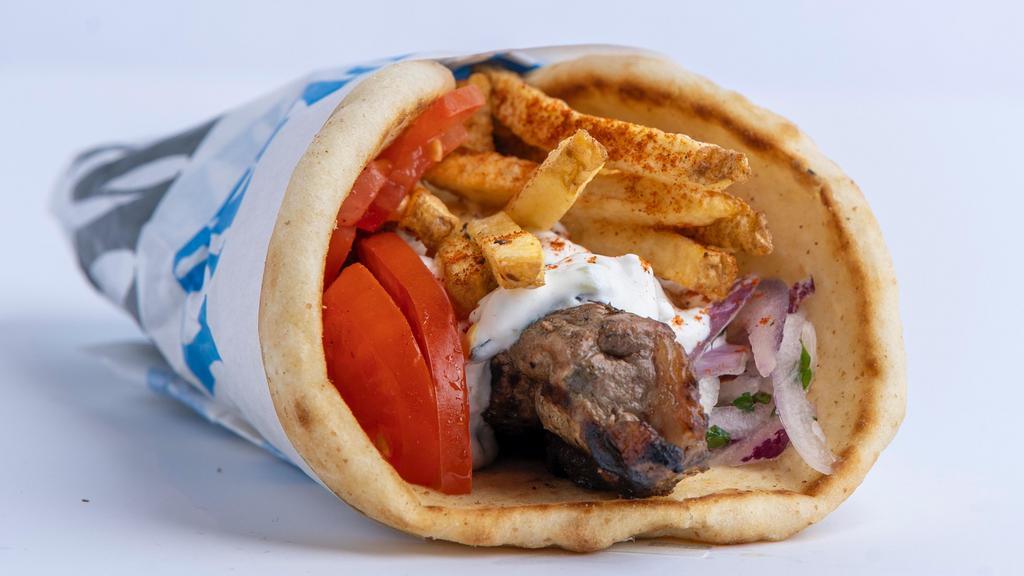 Pork Souvlaki Pita · Seasoned pork cubed and skewered on a stick, cooked over open flame and served on a warm pita bread filled with fries, tomatoes, onions, and tzatziki sauce.