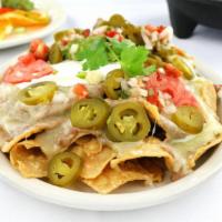 Fiesta Nachos · Homemade tortilla chips topped with refried beans, melted cheese, jalapenos, guacamole, pico...