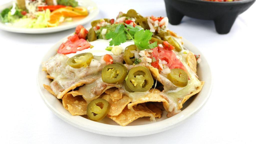 Fiesta Nachos · Homemade tortilla chips topped with refried beans, melted cheese, jalapenos, guacamole, pico de gallo and sour cream.