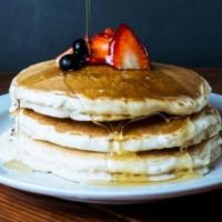 Short Stack Pancakes · Three fluffy pancakes topped whipped butter and maple syrup.