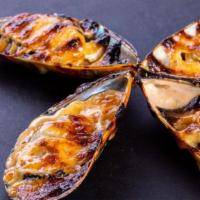 Dynamite Mussels · Green mussels topped with dynamite sauce.