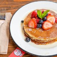 Tres Leches Pancakes · Three Fluffy Pancakes in a house tres leches sauce served with berries.