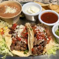 Steak Tacos (2 Pcs.) · Chimichurri marinated steak, topped with pico de gallo and Cotija cheese. Served with fire-r...