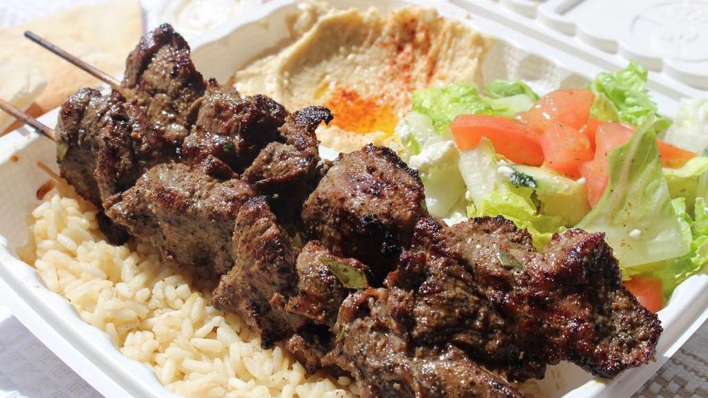 Lamb Kebab · Two skewers flame-broiled lamb cubes served with rice, hummus, Greek salad, and pita bread.