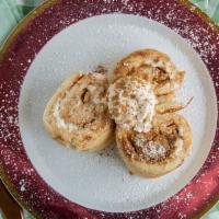 Cinnamon Roll Pancakes · Three rolled pancakes filled with cream cheese cinnamon frosting topped with strawberry, ban...