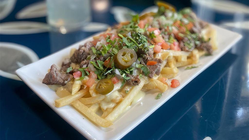 Carne Asada Fries · Crispy fries layered with steak and Cicada cheese dip. Topped with tomato, cilantro, onion, and jalapeño