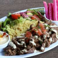 Beef Shawerma Plate · Beef Shawerma topped with tahini sauce served over rice pilaf, side salad, two side picks & ...