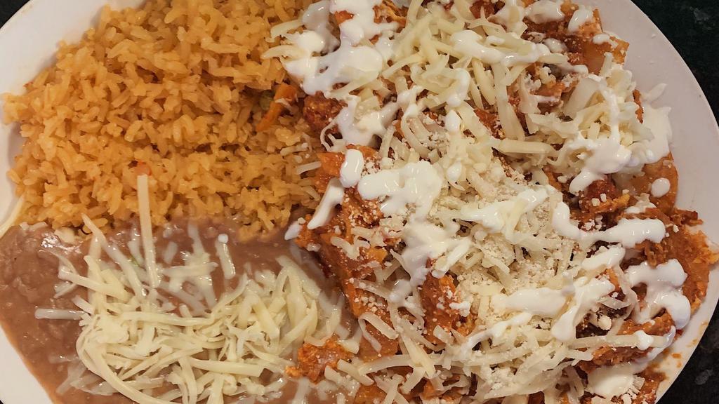 Chilaquiles · Corn tortillas mixed with scrambled eggs and onions, in a spicy sauce topped with cotija cheese and a drizzle of sour cream. Side of rice and beans.