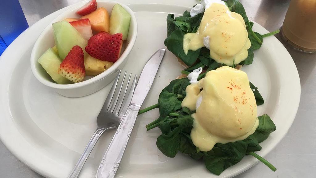 Eggs Florentine · English muffin topped with poached eggs, spinach, sliced tomato, & hollandaise sauce. Served with fruits or roasted potatoes.