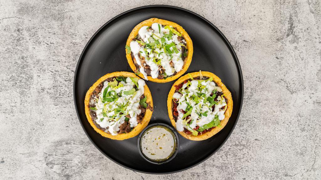 Sopes · Toppings: beans, meat, lettuce, cheese, sour cream, cilantro, and salsa.