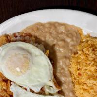 Chilaquiles · Corn tortilla chips, simmered in a red salsa, and topped with cheese and onions, and sour cr...