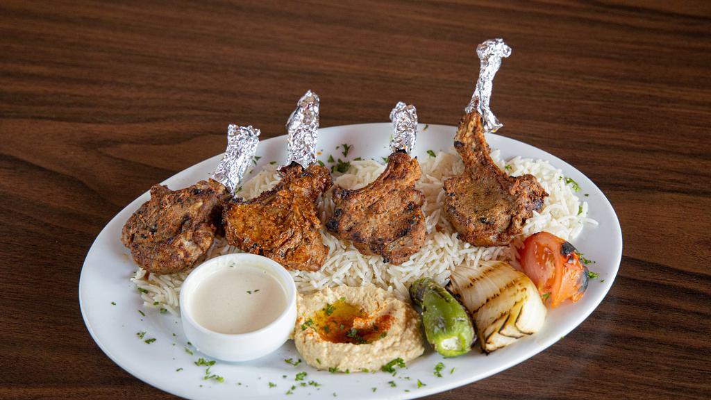 Lamb Chops · Succulent baby lamb chops of four marinated and charbroiled over an open flame and served with hummus, rice (pilaf), tahini sauce, grilled veggies, and pita bread.