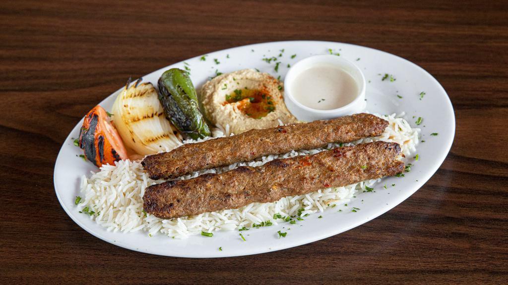 Adana Kebab Plate · Skewered of extra lean ground beef and lamb mixed with parsley, onion, spices are charbroiled and served with hummus, rice (pilaf), tahini sauce, grilled veggies, and pita bread.
