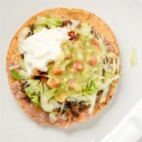 Tostada · Crispy corn tortilla topped with refried beans, lettuce, sour cream, cheese, and guacamole.