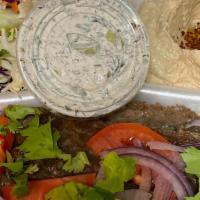 Beef Gyro Plate · Beef gyro served over rice, with sides of hummus, salad, tzatziki, and pita bread.