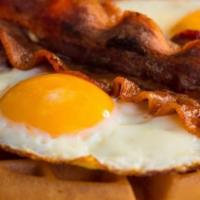 Waffle & Eggs · Two eggs and bacon on top of a classic waffle served with syrup and butter..