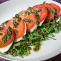 Caprese Salad · Fresh mozzarella and fresh tomatoes with homemade pesto sauce on a bed of fresh cut lettuce.