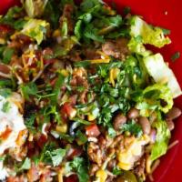 Taco Salad · A crisp flour tortilla shell layered with refried beans, iceberg lettuce, cheddar cheese, ch...