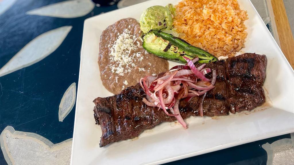Arrachera · Marinated steak, garnished with grilled red onion, fried jalapeno and guacamole. Served with red rice and refried beans, and your choice of flour or corn tortillas.