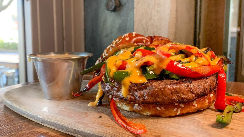 Cinco De Pepper Burger · pepper-crusted beef patty, beer cheese sauce, poblano pepper, jalapeno pepper, red bell pepper, pickled red onion, and habanero pepper aioli on a pretzel bun