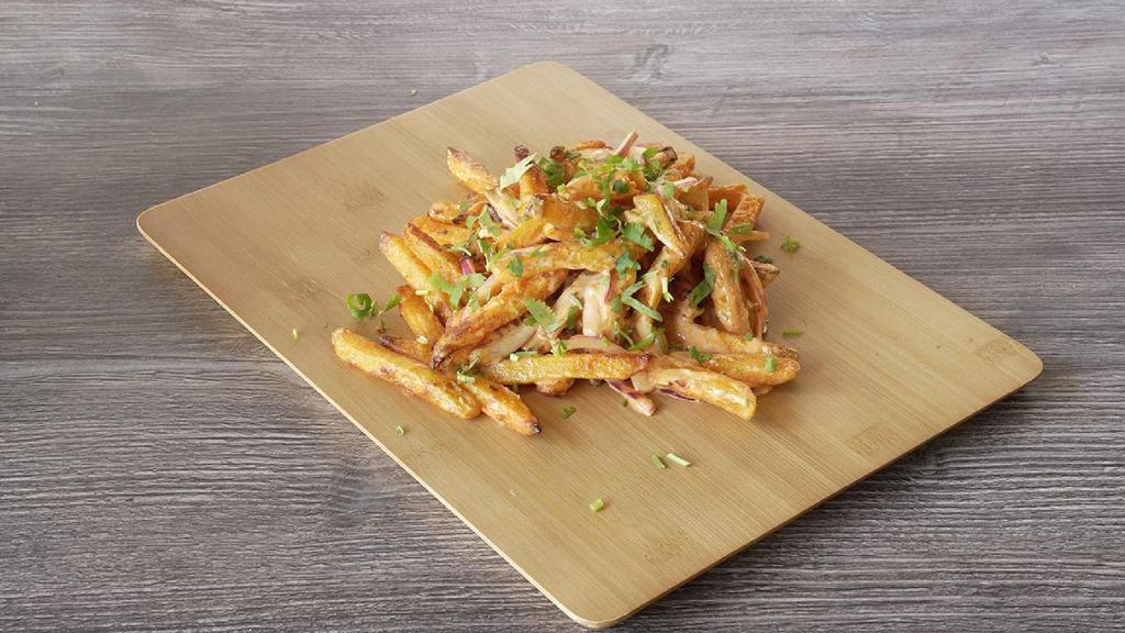 Masala Fries Twist · Our masala fries twist has sliced red onions, fresh cut; garlic, ginger, and green chilies, tossed in our signature sauce, garnished with  fresh cilantro
