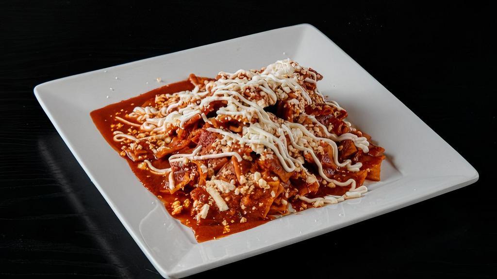 Chilaquiles · Crispy corn tortillas in a green, red or mole sauce.  Topped with sour cream and cheese.