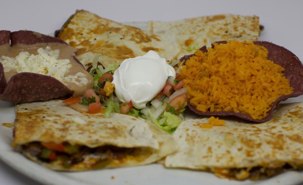 Fajitadilla · Soft flour tortilla stuffed with sliced chicken or steak sauteed with bell peppers and onion. Garnished with guacamole, sour cream and pico de gallo. Served with rice and beans.