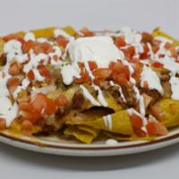 Enchilada Nachos · Nachos topped with refried beans, melted cheese, tomatoes, green onions, enchilada sauce, gu...