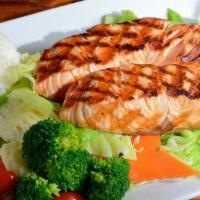 Grilled Salmon · Grilled salmon served atop a bed of cabbage along with sides of rice and macaroni salad.