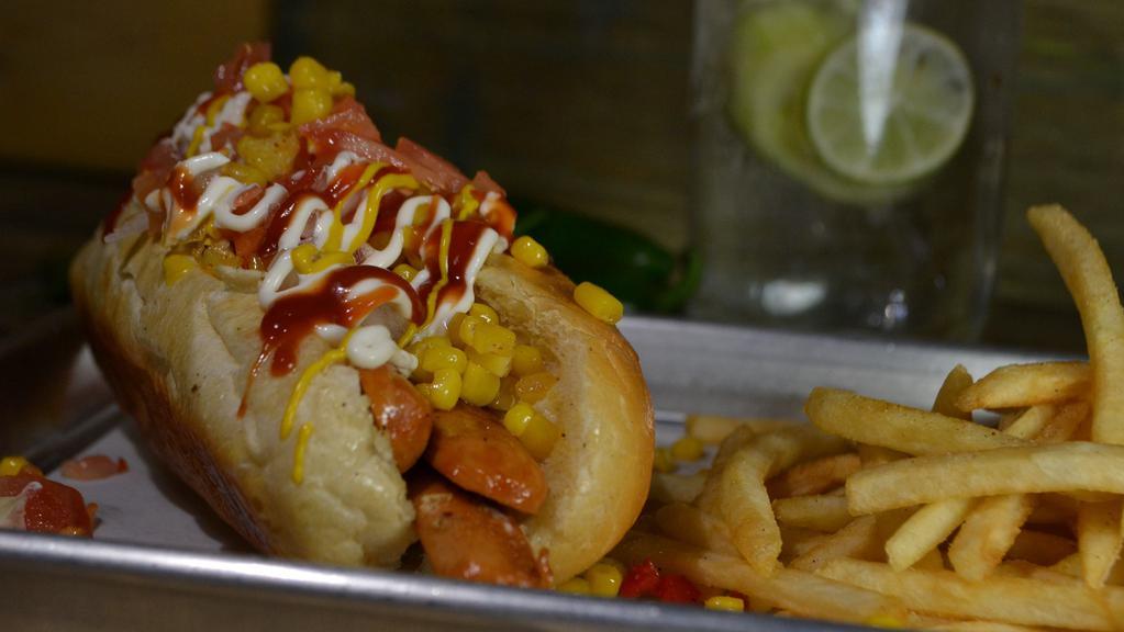 Veggie Dogo · Vegetarian hot dog (apx 74 lb.) topped with fresh tomatoes and onions, ketchup, mayonnaise, mustard, onions, grilled corn and red bell peppers, and spices. A side of fries is included. Grilled serrano pepper upon request.