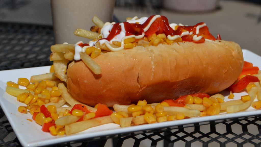 Esquite Dogo · A gourmet 1/4 lb. hot dog wrapped in bacon in a homemade bun, topped with ketchup, mayonnaise, fresh tomatoes, cheese, french fries, grilled corn and red bell peppers, tajin, spices, sour cream. Served with a side of french fries. Grilled serrano pepper upon request.