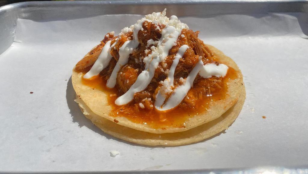 Tinga De Pollo Taco · Shredded chicken breast seasoned with soybean chorizo, onions, chili pods, and spices. Topped with sour cream and dried cotija cheese.