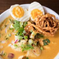 Khao Soi · Spicy Northern Thai yellow curry soup with egg noodles. Topped with onions, chili oil, pickl...