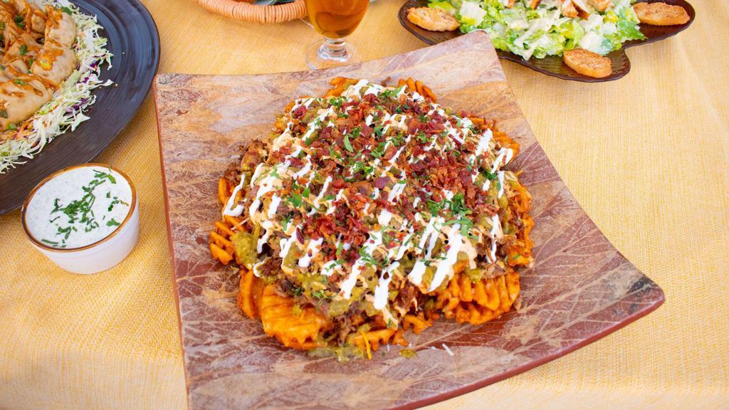 Drunken Pig Fries Platter · Crispy Waffle Fries, Beer-Braised Pulled Pork, Spicy Jalapeno Salsa, Spicy Ranch, melted cheese, sour cream, bacon, and cilantro