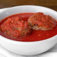 Polpette Della Nonna · Two homemade meatballs in a tomato sauce.