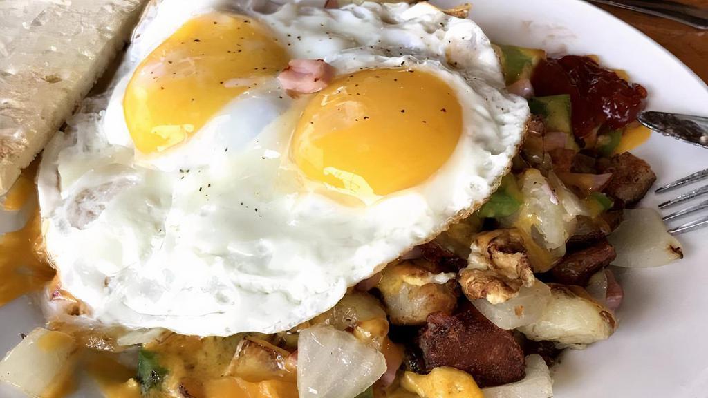The Aviator · Home fried potatoes mixed with onions, bell pepper, diced ham, and cheddar cheese, topped with two eggs.