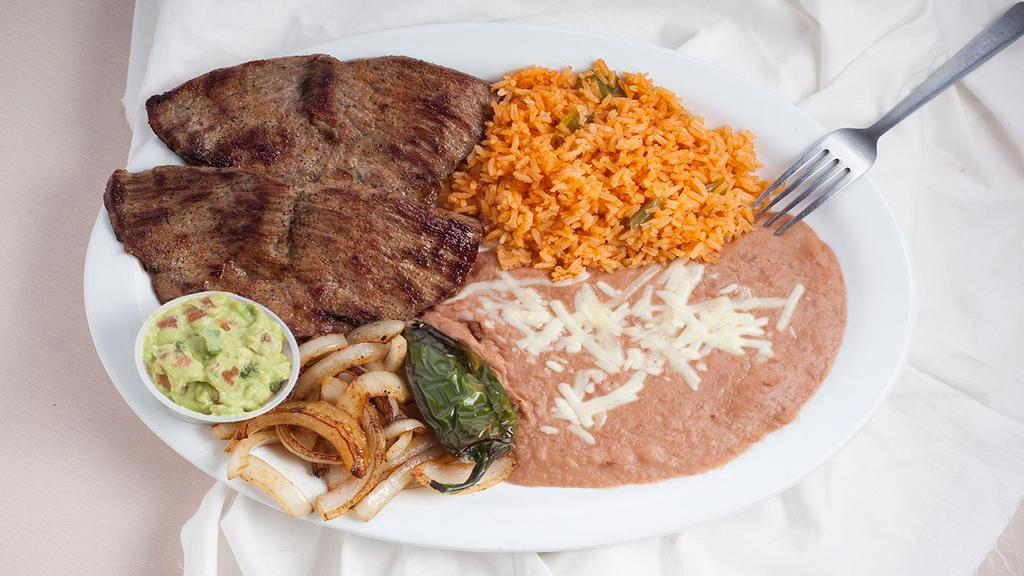 Carne Asada Plate · Seasoned streak, sautéed onions, roasted jalapeños garnished with guacamole. Served with rice and beans, tortillas.