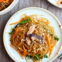 Japchae · Stir-fried sweet potato glass noodles with vegetables. Served with  various side dishes.