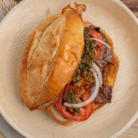 Flank Steak Pepito (Sandwich) · Grilled Flank steak with tomato, onions and Chimichurri sauce on a cheese grated bread.