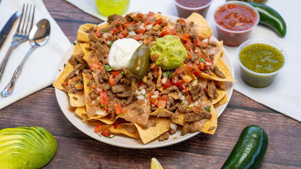 Super Nachos · Chips, refried beans, Monterrey jack cheese, choice of meat, onions, cilantro, tomatoes, sour cream, guacamole, and a whole jalapeno on top.