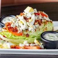 Wedge Salad · Cold wedge of Iceberg lettuce topped with egg, tomato, bacon, blue cheese crumbles and blue ...