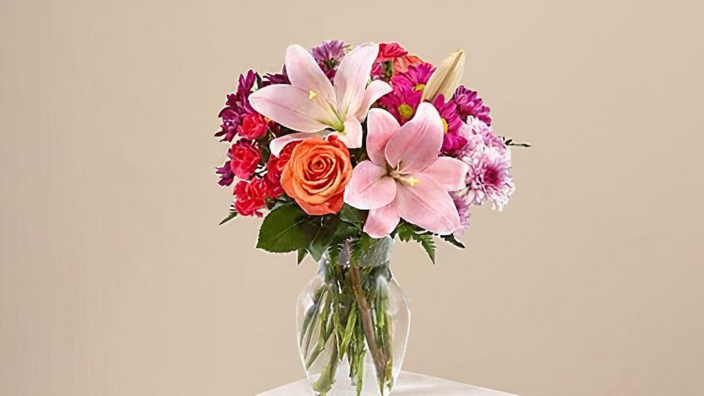 Light Of My Life Bouquet · The Light of My Life Bouquet blossoms with brilliant color and a sweet sophistication to create the perfect impression! Pink Lilies make the eyes dance across the unique design of this flower bouquet, surrounded by the blushing colors of orange roses, lavender cushion poms, hot pink carnations, and lush greens. Vase included. Please Note: The bouquet pictured reflects our original design for this product. While we always try to follow the color palette, we may replace stems to deliver the freshest bouquet possible. Item # C5375S
