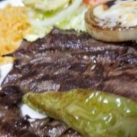 Carne Asada · Sliced grilled steak with grilled onions on top and served with rice, beans, fresh guacamole...