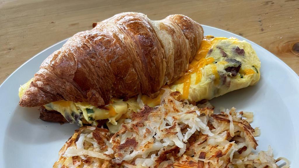 Croissant Breakfast Sandwich · Fresh baked croissant, eggs, bacon, chives, Cheddar served with potatoes.