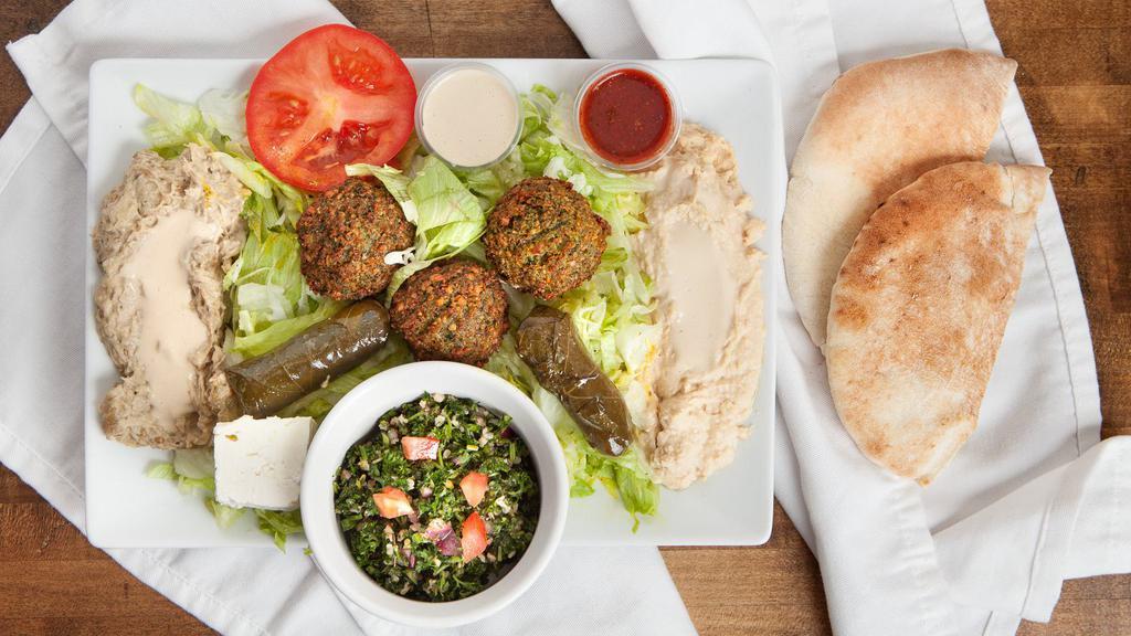 Falafel Delight Plate · A delicious mixture of garbanzo beans, herbs, and spices, served with tahini, lettuce, tomato, hummus, baba ganoush (eggplant) and tabouli, dolma, and feta.