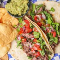 Grilled Steak Tacos (2) · Delicious pieces of ribeye steak, wrapped in warm flour tortillas, topped with red onions an...