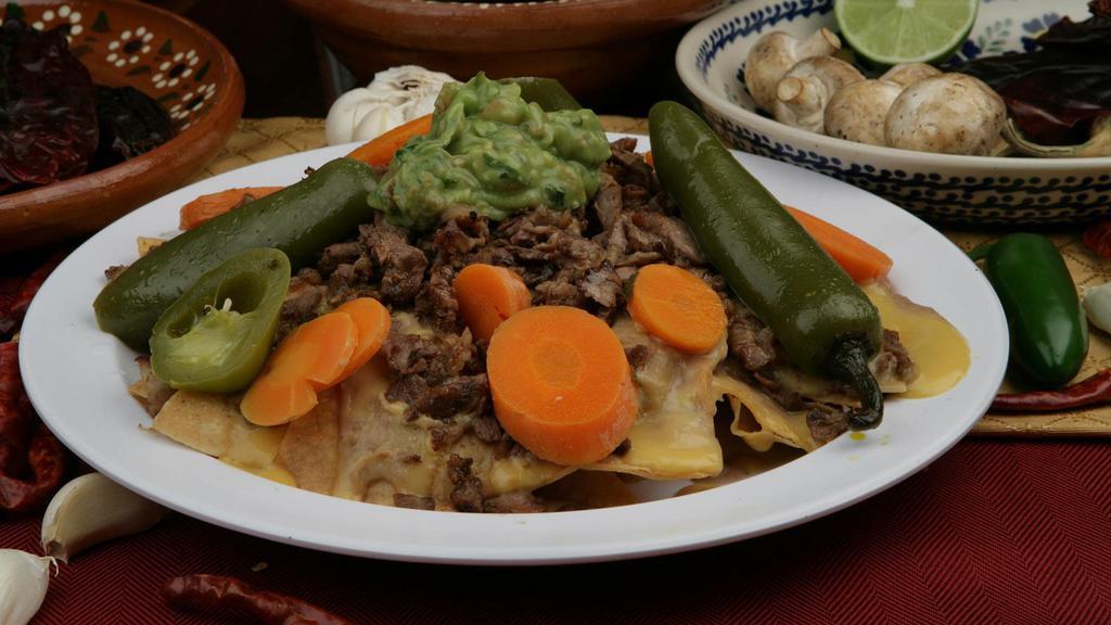 Nachos Machos · Corn chips topped with beans, nacho cheese, choice of meat, guacamole, and chile curtido.