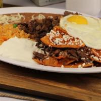 Chilaquiles Con Huevo & Asada · Delicious Mexican chilaquiles with red or green salsa topped with two eggs and carne asada.